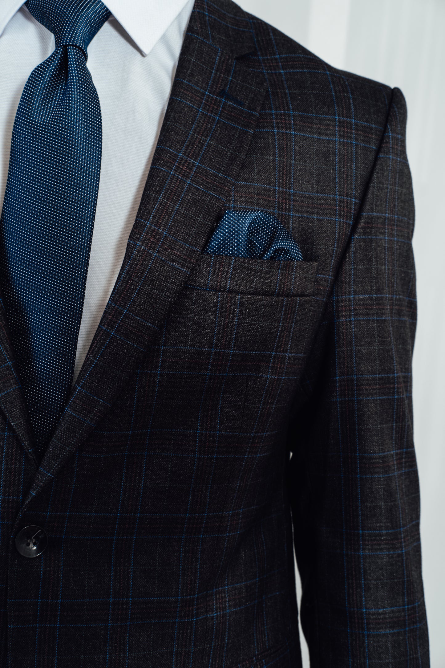 Model draagt donker blauw kostuum met kleine ruit van Suitify